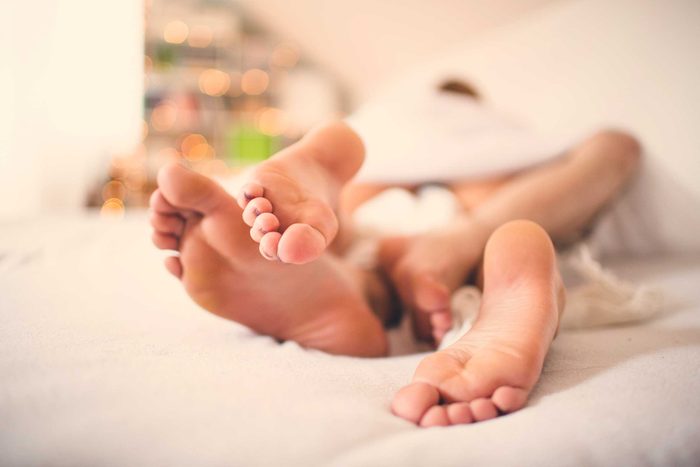 couple's legs entwined in bed
