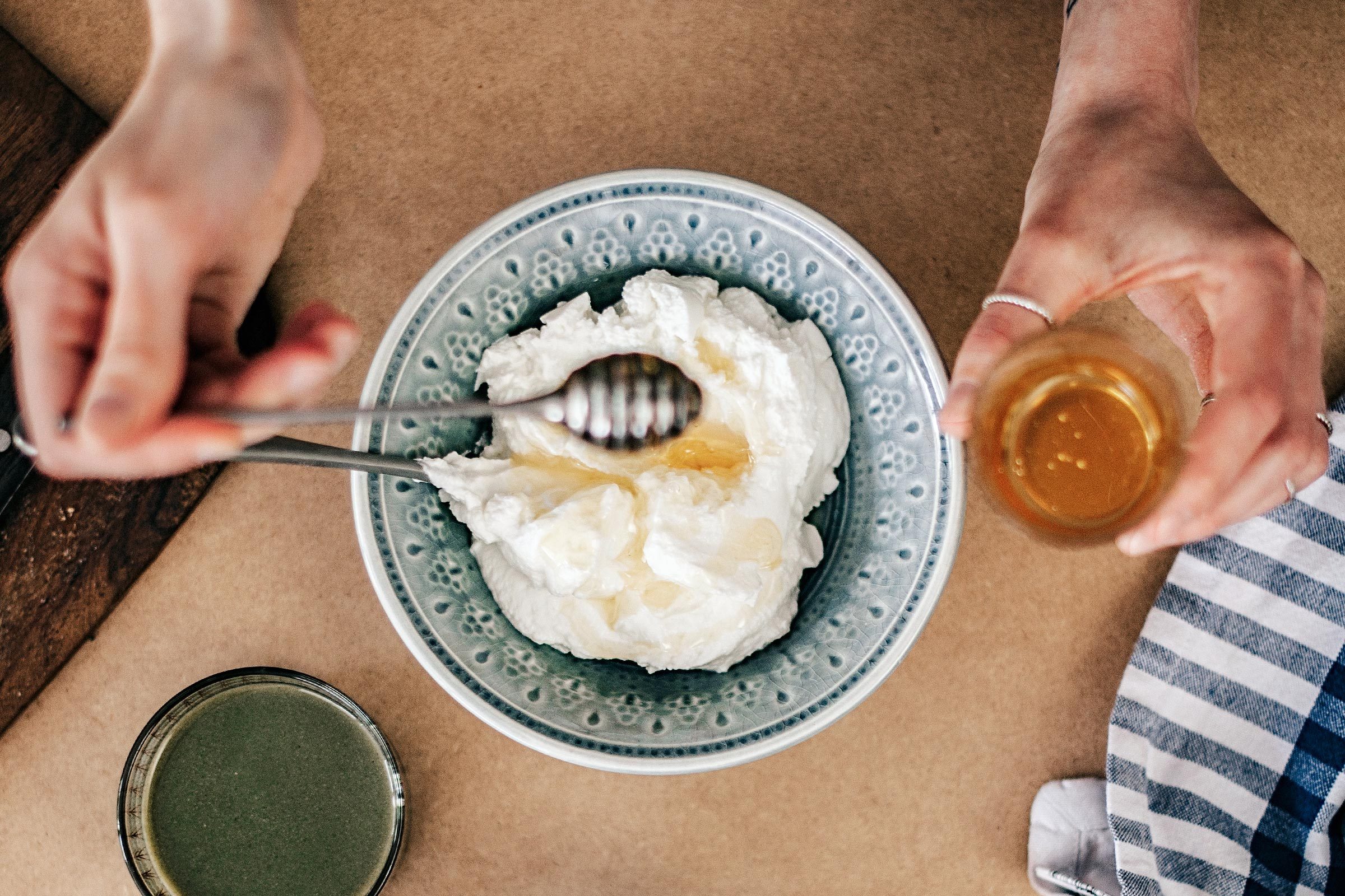 someone drizzling honey over yogurt