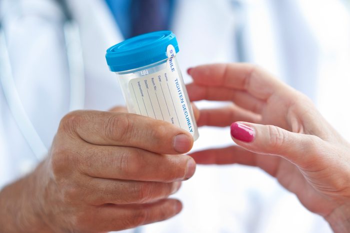doctor passing a patient a collection bottle