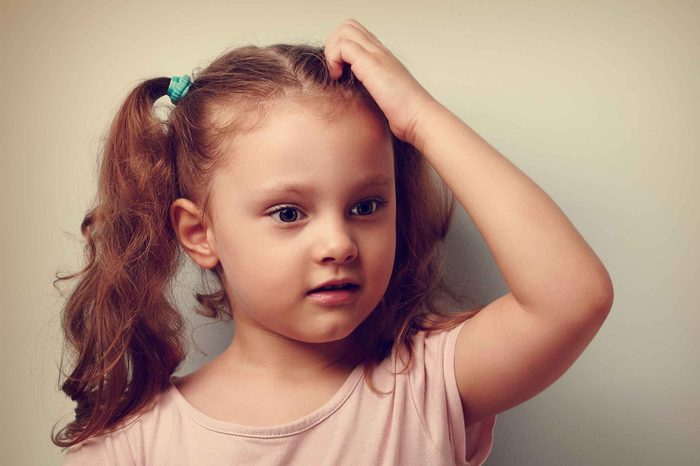 Little girl with pigtails itching her scalp.