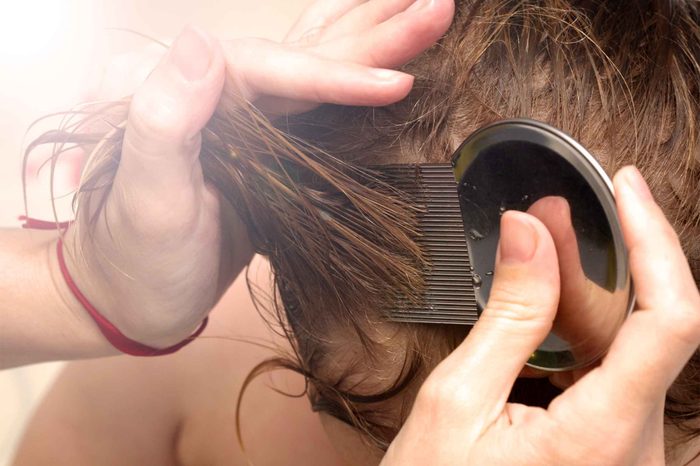 Person combing through a child's hair with a nit comb.
