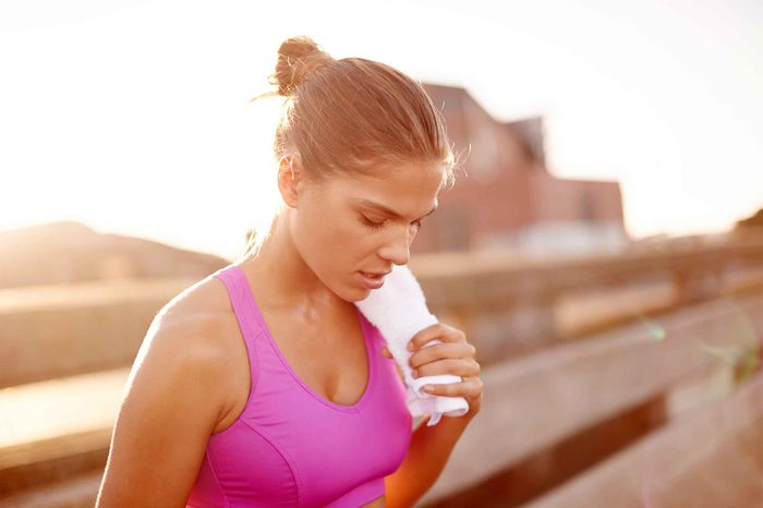 woman in exercise bra outdoors, breathing heavily