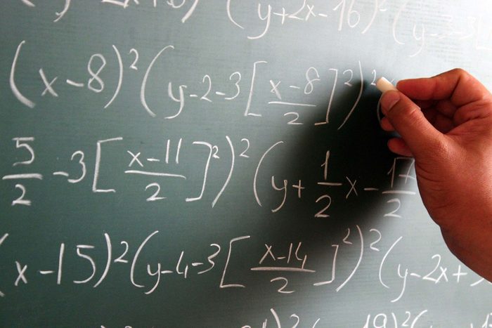hand writing numbers on chalkboard