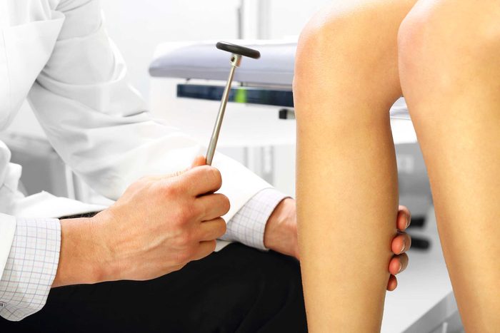 close-up of doctor testing knee reflex with rubber hammer