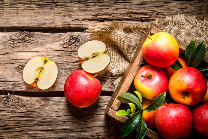 box of red apples next to halved and whole apples