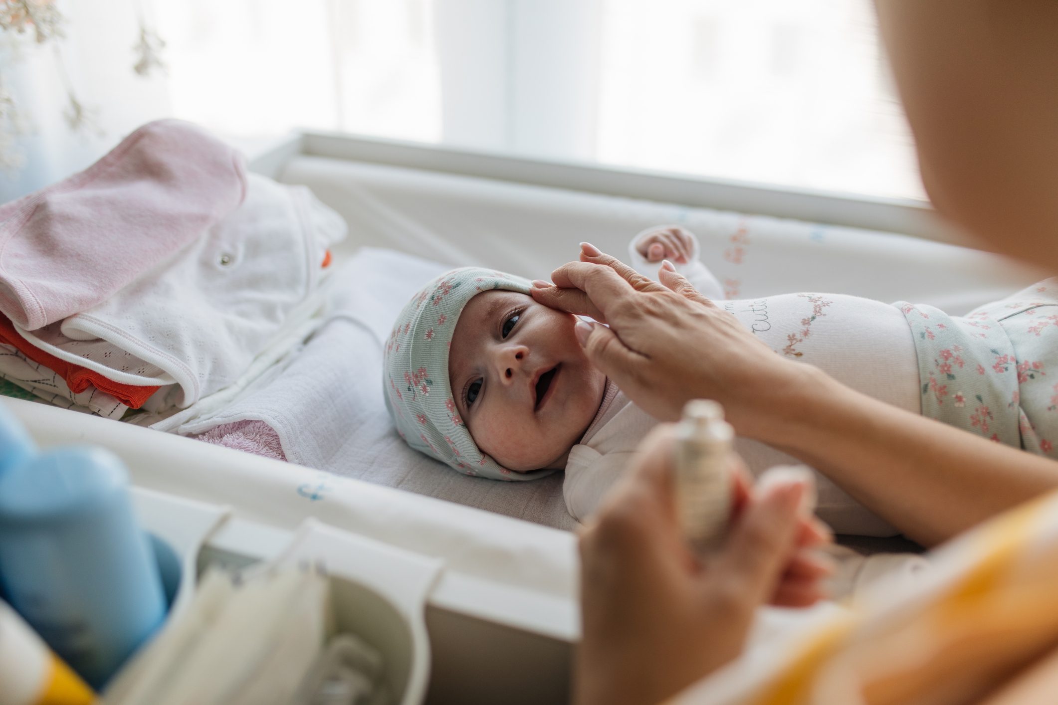mother applying cream on baby's face