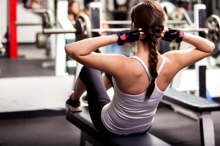 young woman doing sit ups at gym