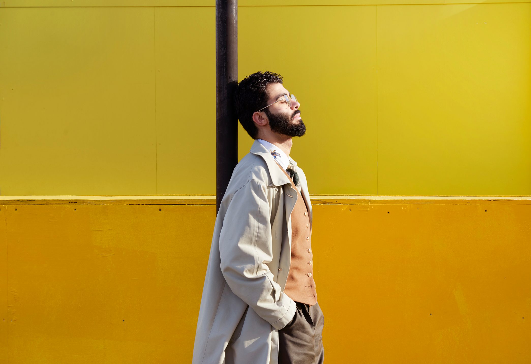 man leaning on street pole