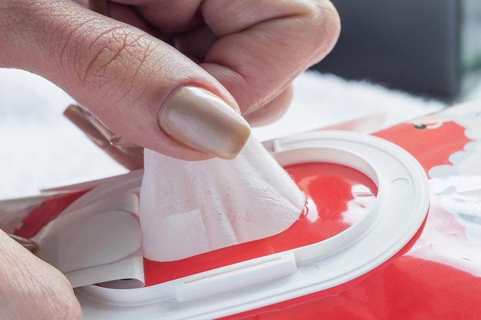 A woman pulling a towelette out of a box.