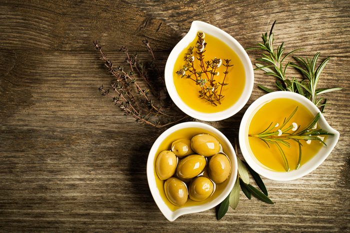 three bowls of olive oil with olives and spices