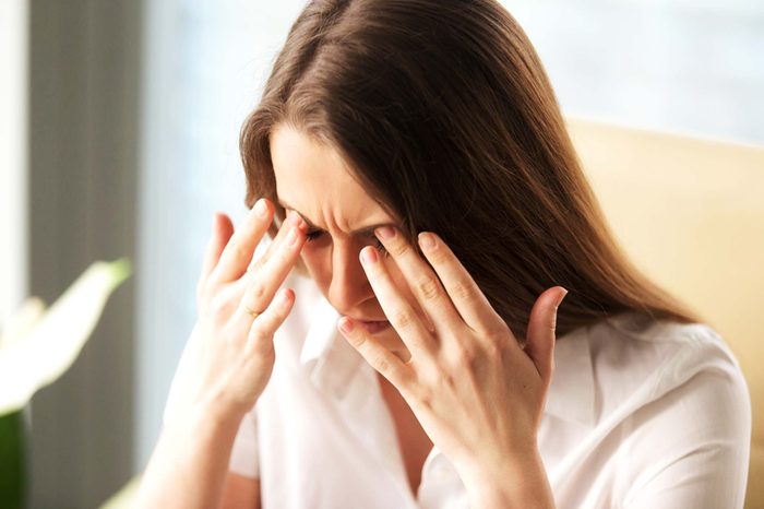 woman in pain pressing her hands into her eyebrows