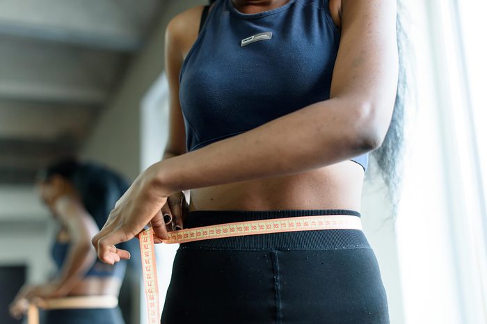 woman using tape measure on waistline