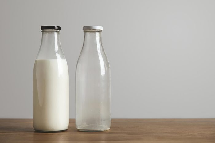 side by side mild bottles on a wooden surface, one full, one empty