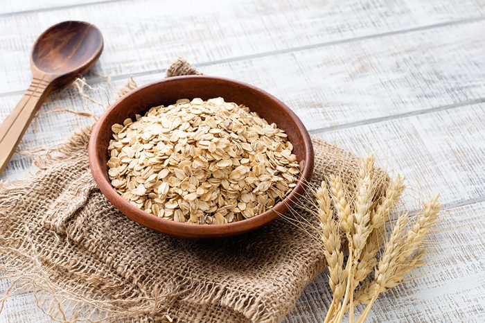 dry oats in a wooden bowl on a folded burlap sack