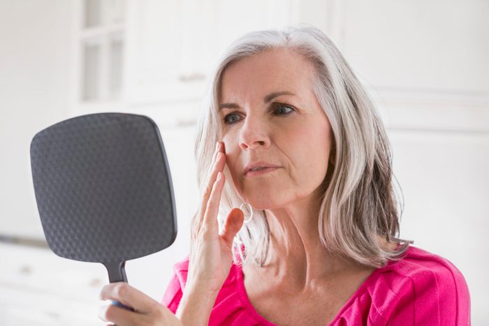 woman looking in handheld mirror