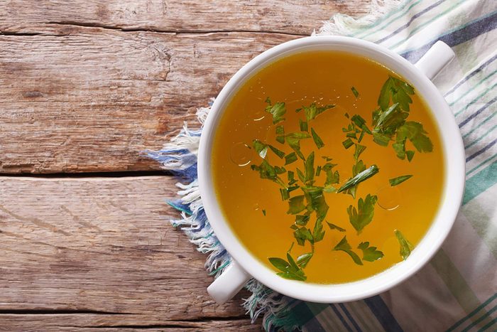 bowl of broth with chopped parsley on top