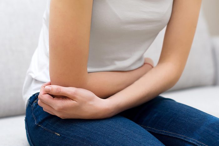 sitting woman holding her arms across her abdomen