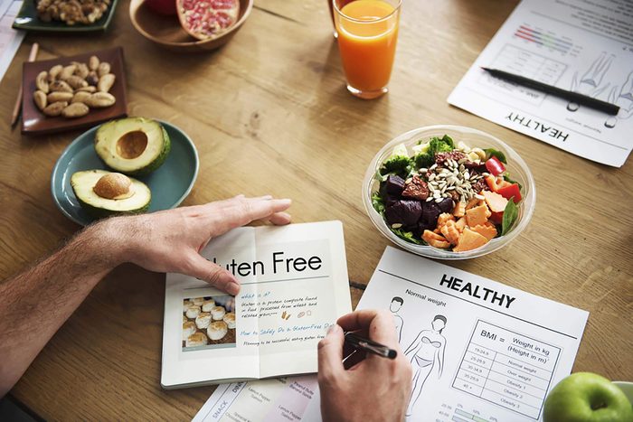 Person looking at a gluten-free chart while eating lunch.