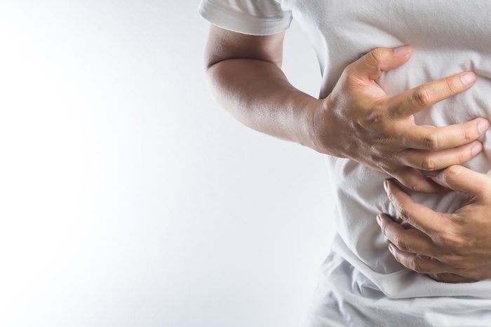 man in a white t-shirt clutching his stomach