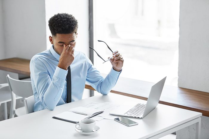 man at his desk rubbing his eyes