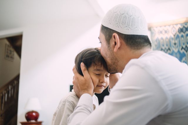 father kissing son on the forehead