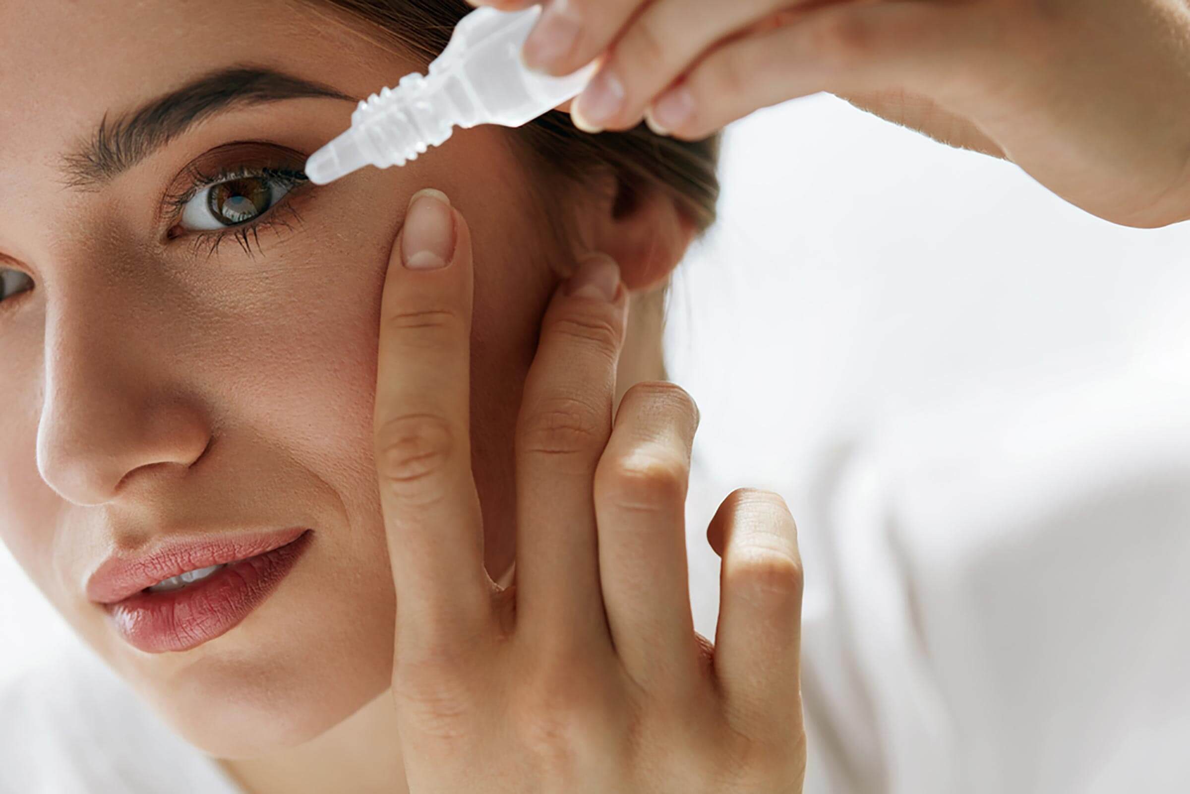 woman putting drops in her eyes