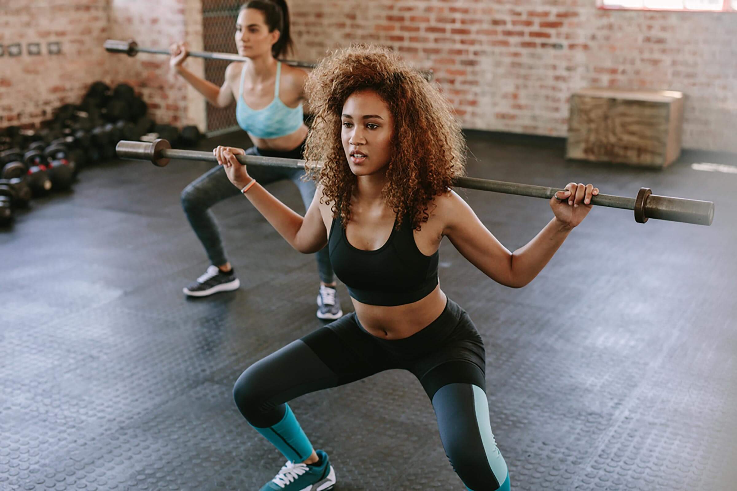 Young exercising with barbell in fitness class
