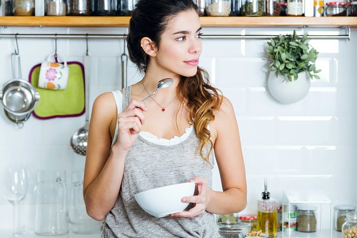 woman in kitchen with bowl and spoon