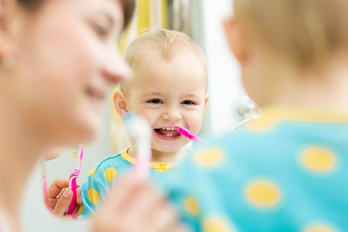 Baby smiling in mirror and brushing teeth