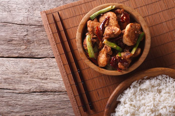 Kung pao chicken fillets in a bowl and rice. horizontal view from above