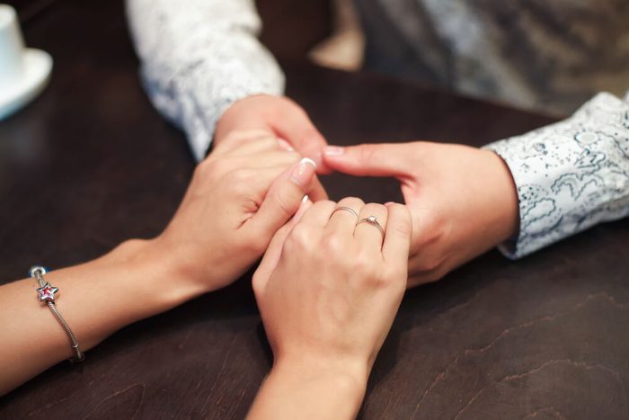 Young couple in love clasping hands across the table in cafe.