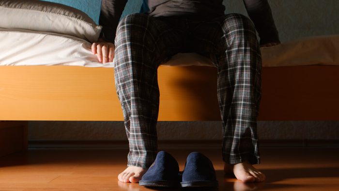 Man sits on a bed in the night at home