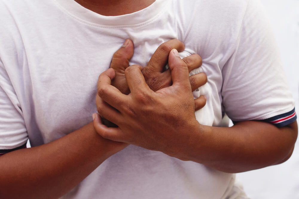 Hand Squeeze The Chest In Pain Over White Background