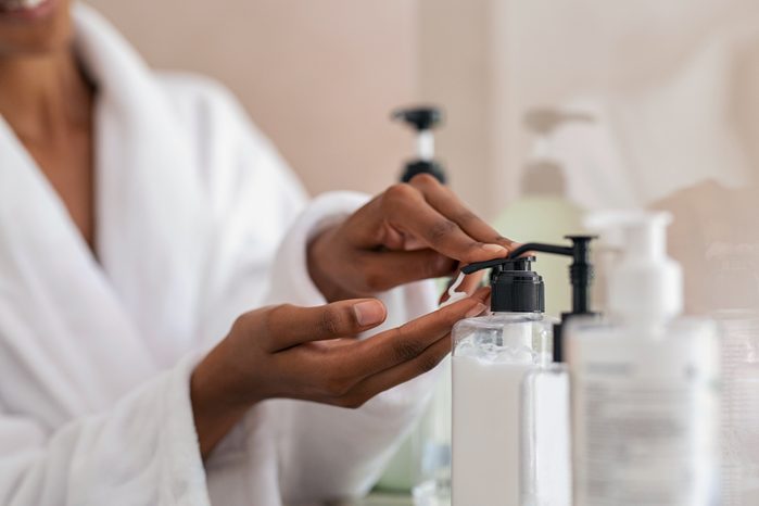 woman taking body lotion from dispenser