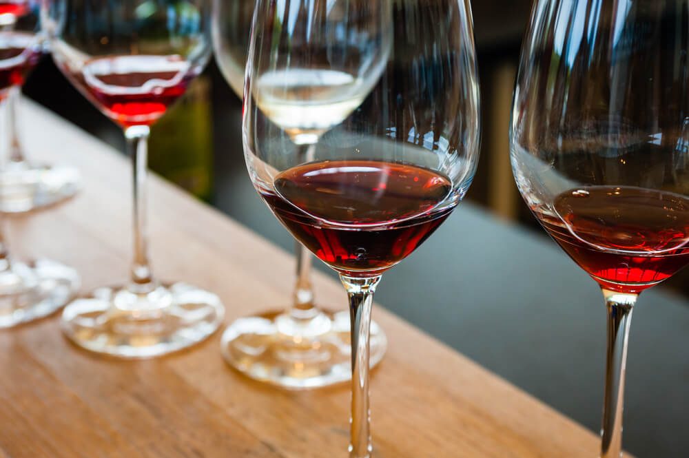 Detail of glasses with red wine samples, on wood counter.