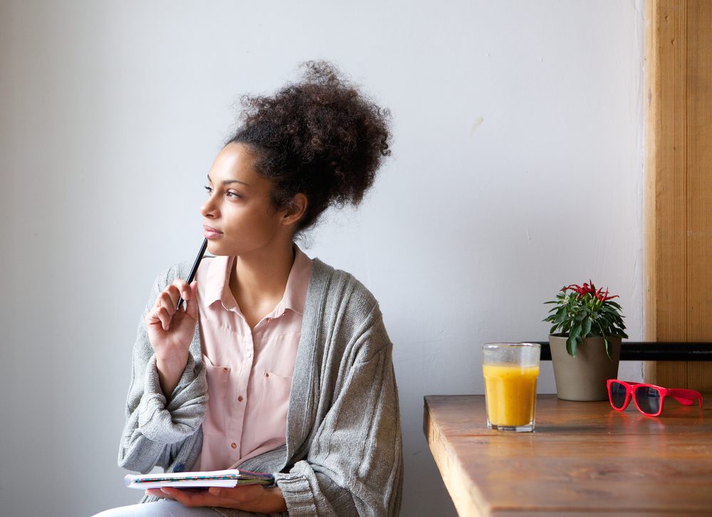 woman sitting and thinking with pen and paper