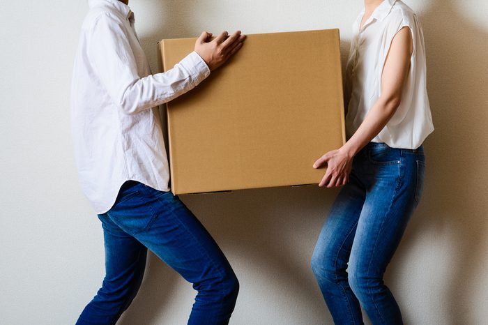 man and women carrying a large cardboard box