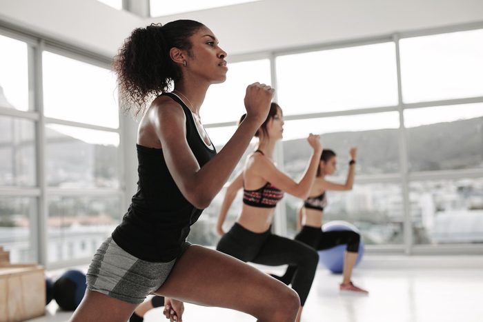 Young woman in sportswear doing exercise during intensive circuit training in gym class. Females working out together in the health studio.