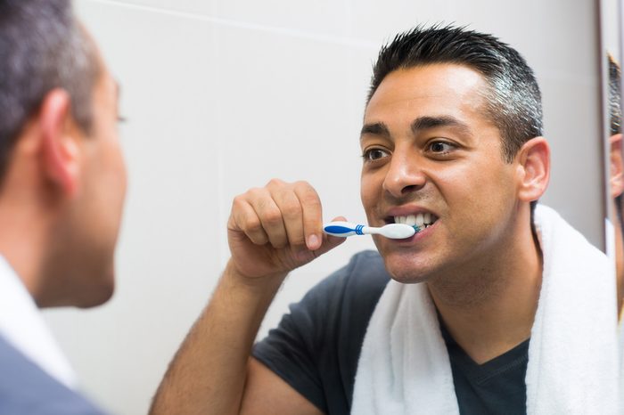 Man brushing his teeth while looking in the mirror