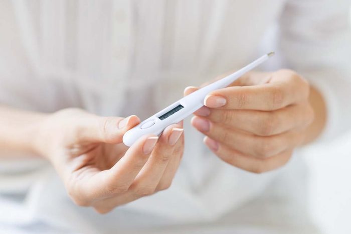woman holding a digital therometer