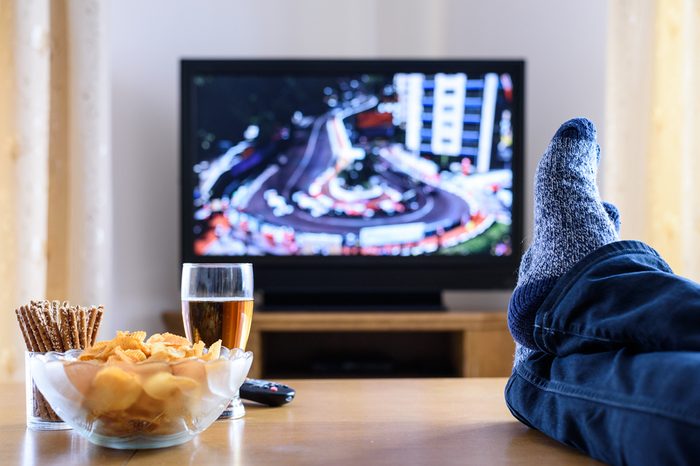 Guy watching TV in living room with feet on table