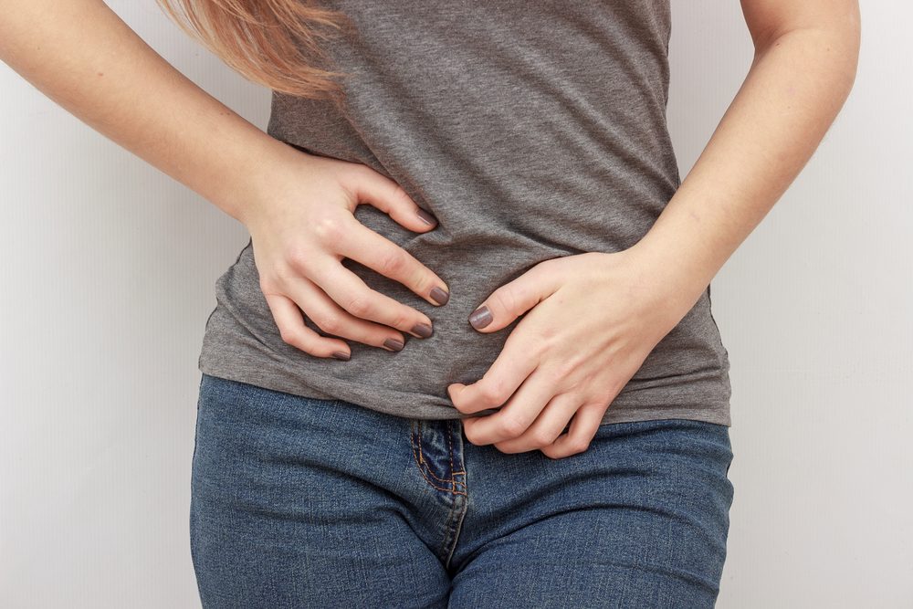 Young casual woman is having stomach ache. Woman making heart shape on her stomach. Gynecology, period, female healthcare, digestive system, Urinary Tract Infections