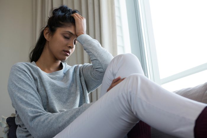 Tired young woman sitting on sofa at home