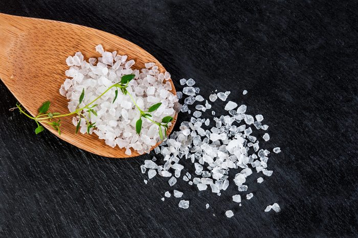 Sea salt on a wooden spoon over black slate background, selective focus, close up, salt,