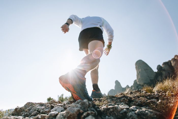 Strong calves leg with muscles of ultra marathon runner and athlete during race or marathon on mountain path trails, professional running shoe sole of sneaker and rocky terrain surface