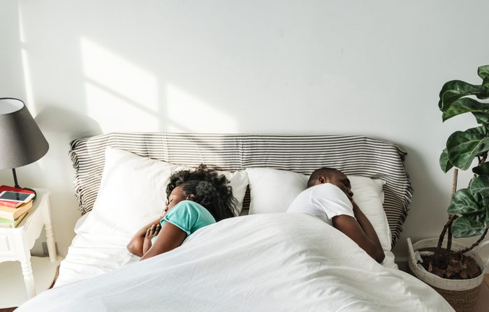 couple sleeping back to back in bed