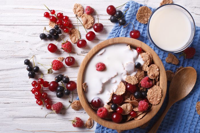 Cereal with milk and fresh berries in a wooden bowl.
