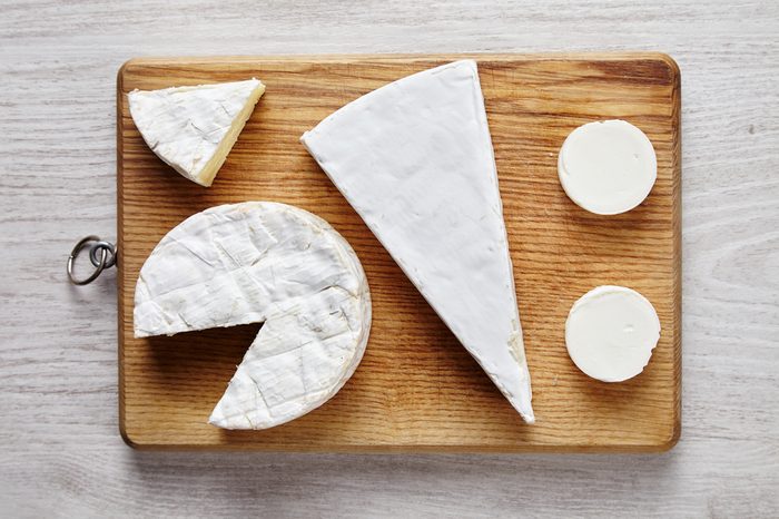 Avangard white soft cheeses: goat, brie, camembert on wooden des