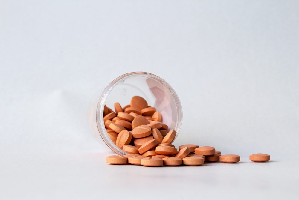 Prescription pill bottle spilling pills on to surface isolated on a white background. Orange medicine for patient in hospital and people who feel sick,ill.
