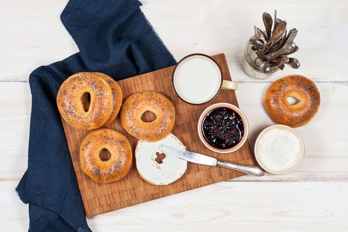 Fresh homemade Poppy bagels bread with cup of milk, cream cheese and berries jam.